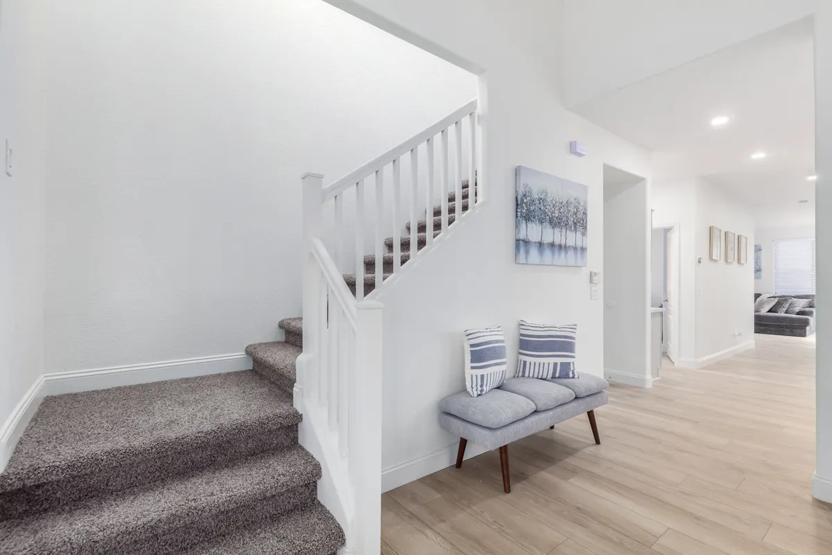 The entry area features a staircase and a cozy seating arrangement, accented by tasteful artwork. This space makes a strong first impression, setting the tone for a welcoming home. Natural light filters in, tying the entry visually to the broader living spaces and supporting the open, inviting narrative.