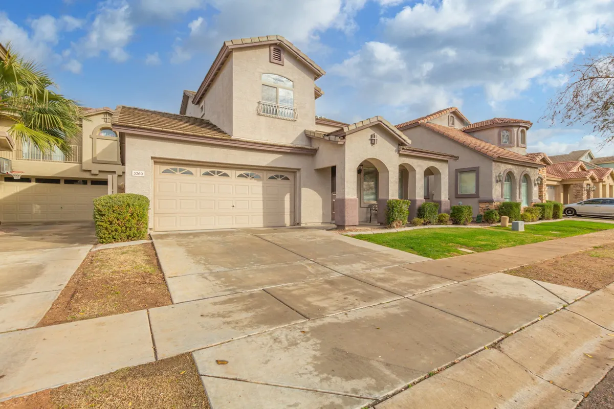A welcoming view of the home's front entryway, garage door, and a landscaped front yard. The scene is bathed in sunset light, evoking the inviting nature of the neighborhood and easy access to nearby amenities.