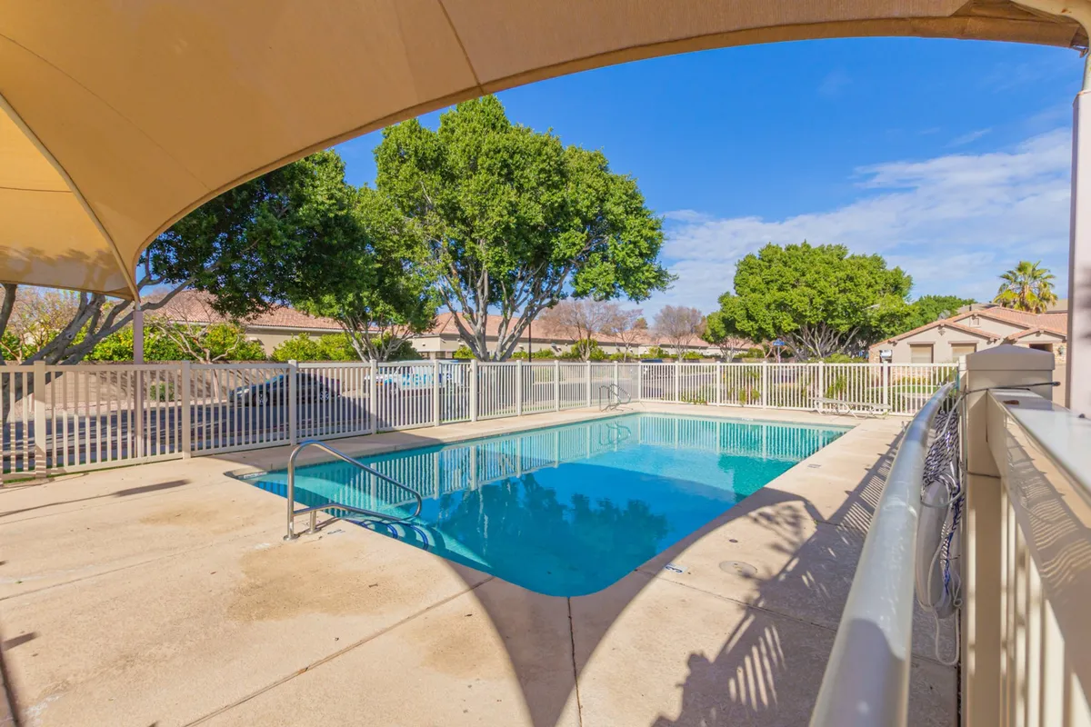 A shimmering swimming pool surrounded by mature trees and enclosed by a fence, creating a serene and secure environment perfect for family enjoyment and social gatherings.