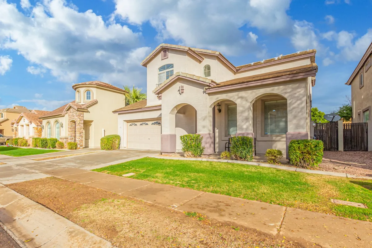A two-story home featuring a welcoming front porch, manicured lawn, and views of neighboring houses, all bathed in bright natural light. The inviting facade and tidy landscape suggest a prime, central neighborhood setting.